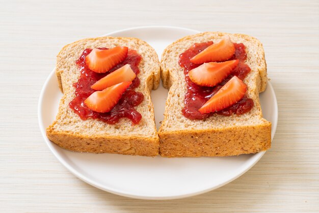 pane integrale fatto in casa con marmellata di fragole e fragole fresche