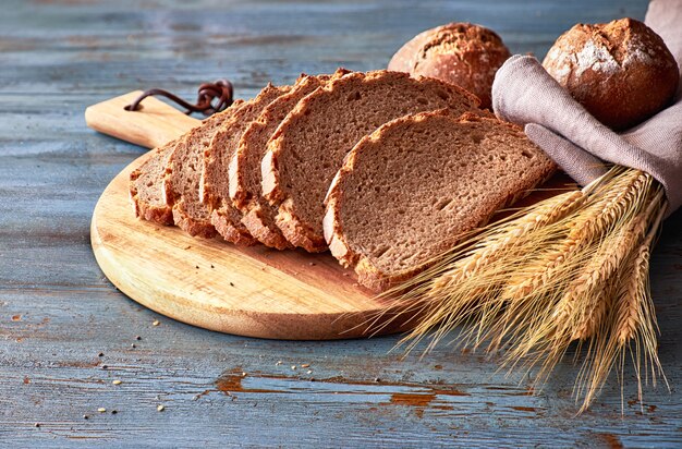 Pane integrale tagliato a bordo con focacce e spighe di grano dorato