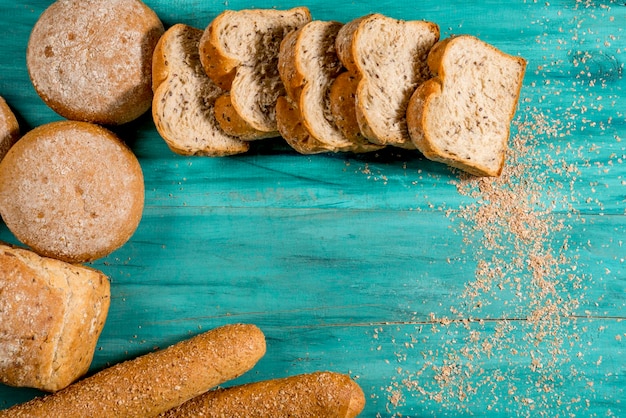 Pane intero affettato su legno blu strutturato, vista dall'alto, spazio per il testo.