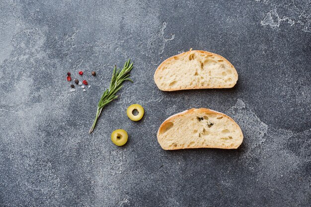 Pane italiano ciabatta con olive e rosmarino su uno sfondo di cemento scuro