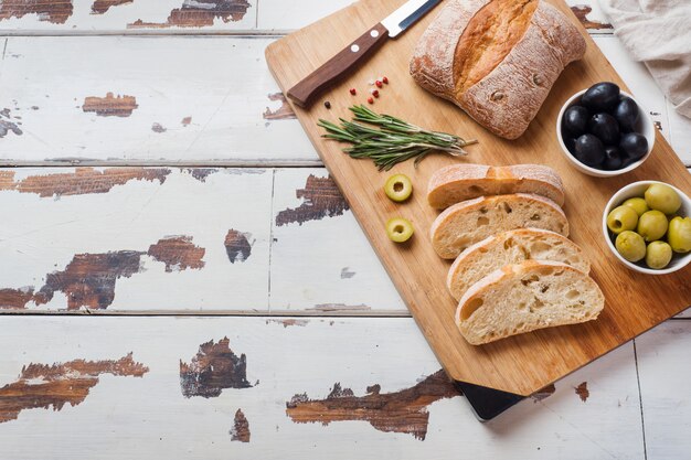 Pane italiano di ciabatta con olive e rosmarino su una tavola di legno