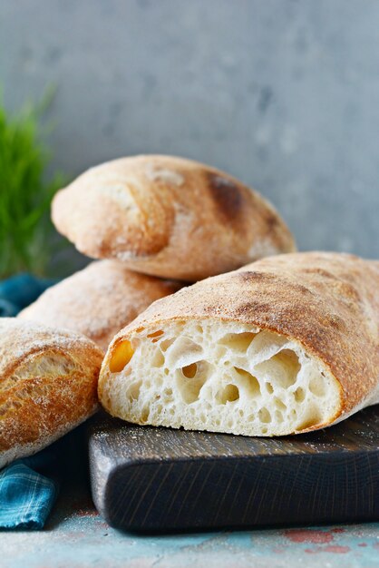 Pane italiano di recente al forno di ciabatta sul tagliere di legno. Vista dall'alto