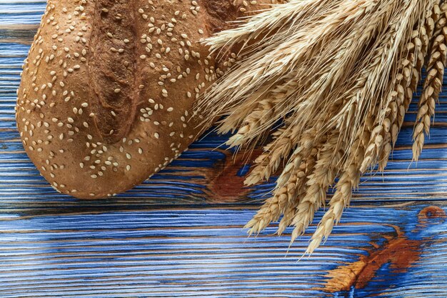 Pane marrone delle spighe di grano su fondo di legno dell'annata