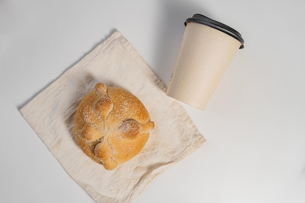 Pane messicano tradizionale dei morti e tazza di caffè di carta sul tavolo bianco