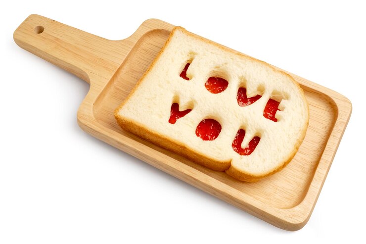 Pane morbido con lettere di iscrizione Love You messo su marmellata di ciliegie servito su vassoio di legno
