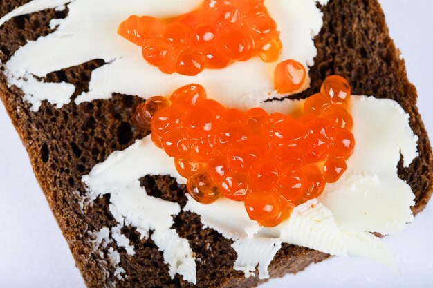 Pane nero ai cereali con burro e caviale rosso. Primo piano estremo