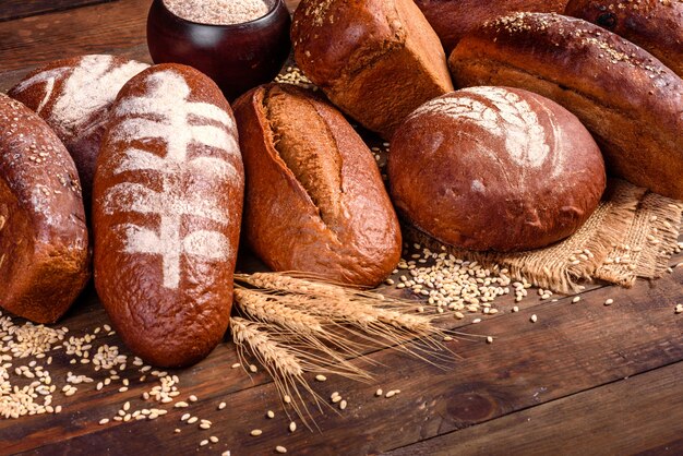 Pane nero al forno fresco su un fondo di legno marrone. Pane tradizionale appena sfornato su uno sfondo scuro.