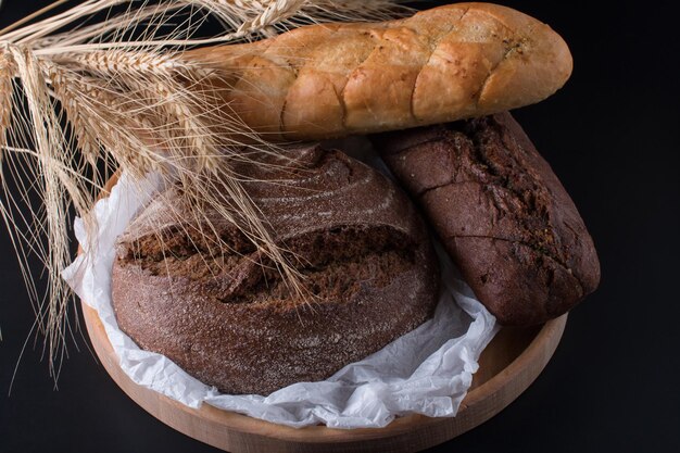 Pane nero rotondo fresco con una crosta croccante Primo piano su sfondo nero