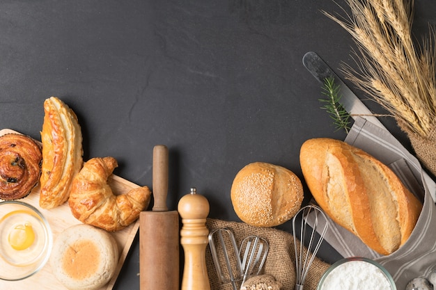 Pane o forno casalingo con l&#39;attrezzatura fresca dell&#39;uovo, della farina e del forno su fondo di pietra nero