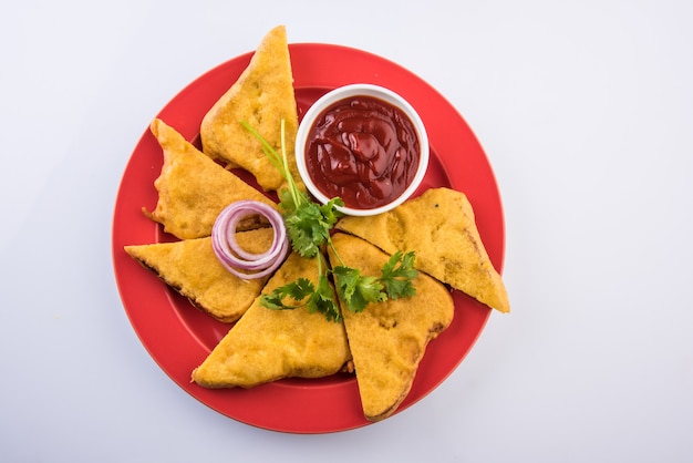 Pane Pakora o pakoda servito con ketchup, peperoncino verde e fette di cipolla, popolare spuntino indiano all'ora del tè. Messa a fuoco selettiva