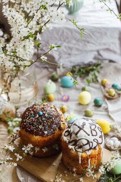 Pane pasquale fatto in casa e uova di pasqua tinte naturali con fiori primaverili su tovagliolo di lino su tavola rustica Cibo pasquale tradizionale Buona Pasqua