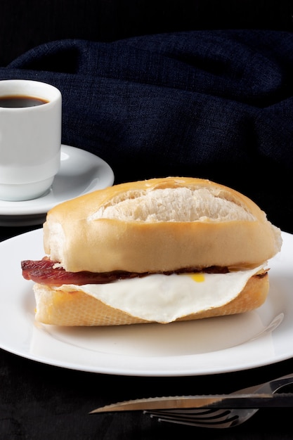 Pane ripieno di uova e pancetta servito con un caffè nero.