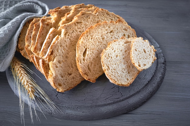 Pane rotondo bianco a strisce con le orecchie del grano su legno rustico grigio