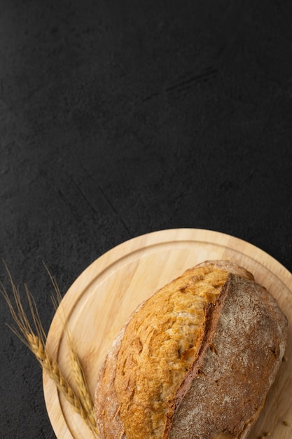 Pane rotondo senza glutine fresco su tavola di legno su sfondo nero