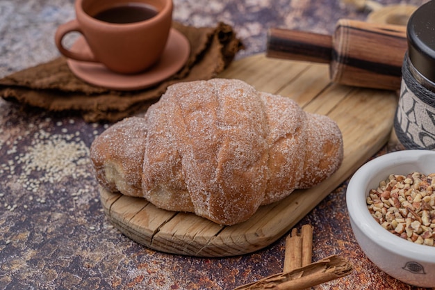 Pane rustico dolce fatto in casa in un tavolo, complemento con una tazza di caffè, pezzo da forno tradizionale