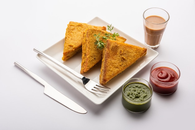 Pane sandwich Pakora o pakoda a forma di triangolo servito con ketchup di pomodoro, chutney verde, spuntino indiano popolare per l'ora del tè