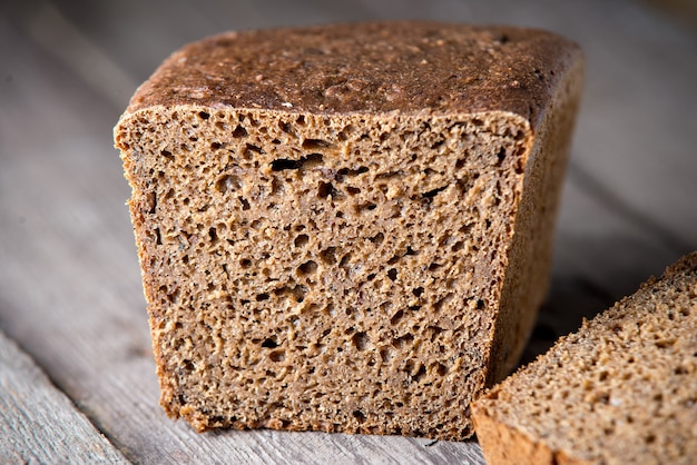 Pane sano appena sfornato su fondo di legno vecchio. Pane di farina integrale.