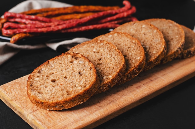 Pane scuro di grano intero sano con semi sul tagliere di legno