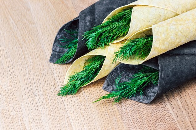 Pane sottile pita bianco e nero arrotolato in una cannuccia con verdure