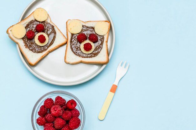 Pane tostato con burro di arachidi, formaggio e lampone su sfondo blu piatto. Bambini bambino dolce dessert colazione pranzo cibo da vicino.