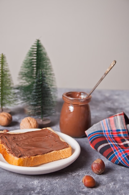 Pane tostato con crema al cioccolato e burro con giocattoli dell'albero di Natale