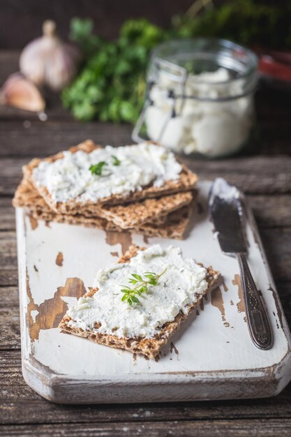 Pane tostato con erbe fatte in casa e ricotta all'aglio su fondo di legno