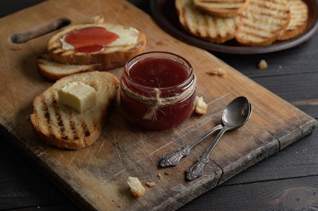 Pane tostato con marmellata di fragole fatta in casa e su tavola rustica con burro per colazione o brunch