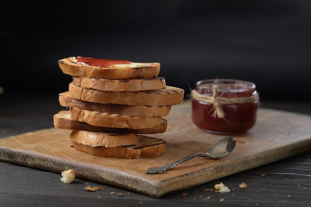 Pane tostato con marmellata di fragole fatta in casa e su tavola rustica con burro per colazione o brunch