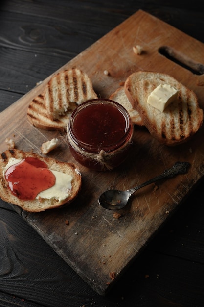 Pane tostato con marmellata di fragole fatta in casa e su tavola rustica con burro per colazione o brunch