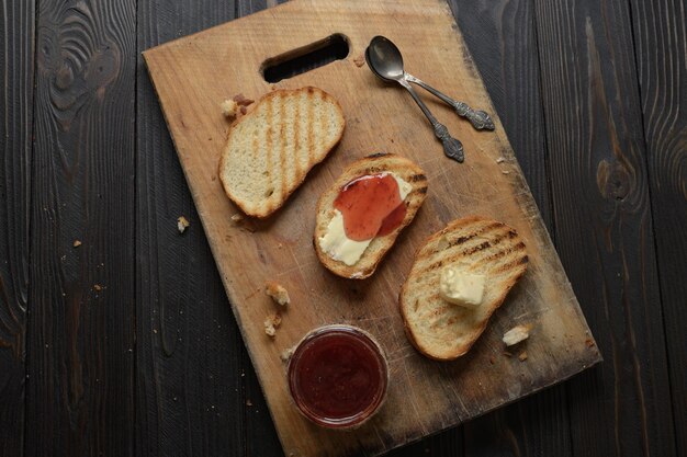 Pane tostato con marmellata di fragole fatta in casa e su tavola rustica con burro per colazione o brunch