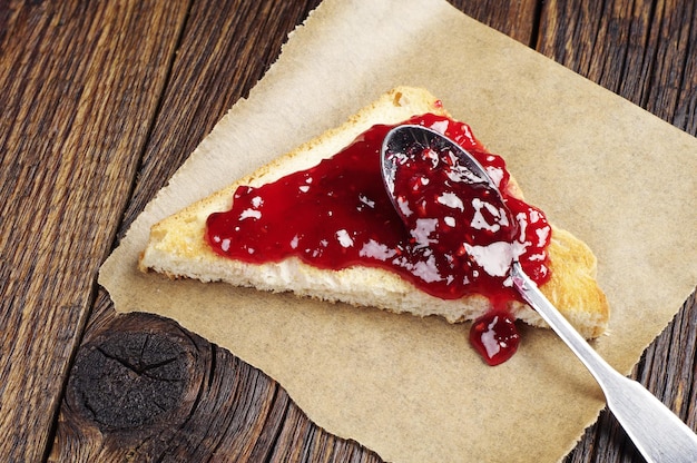 Pane tostato con marmellata di lamponi su tavola di legno scuro