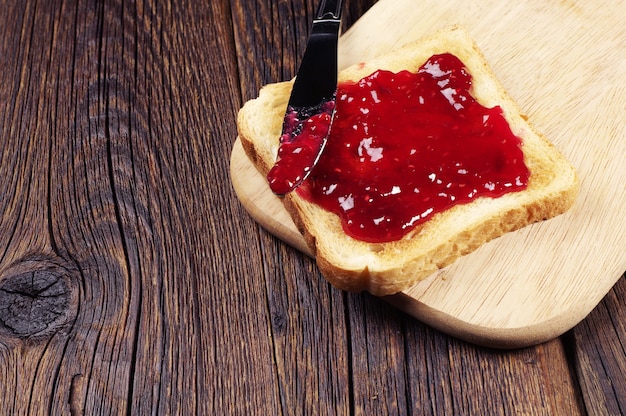 Pane tostato con marmellata di lamponi sul tagliere