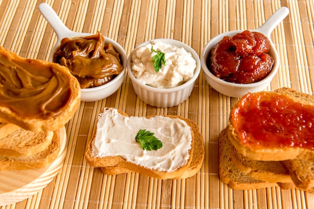 Pane tostato con marmellata, dulce de leche e crema di ricotta sul tavolo della colazione.