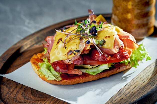 Pane tostato con pancetta, salsicce e formaggio cheddar fuso Sfondo concreto luce del mattino Primo piano fuoco selettivo