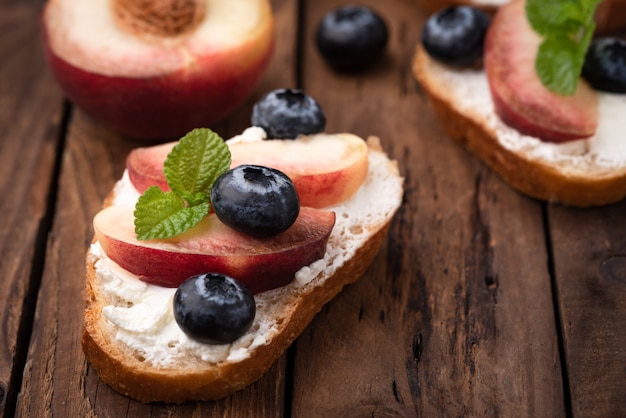 pane tostato con pesche e bacche blu su legno