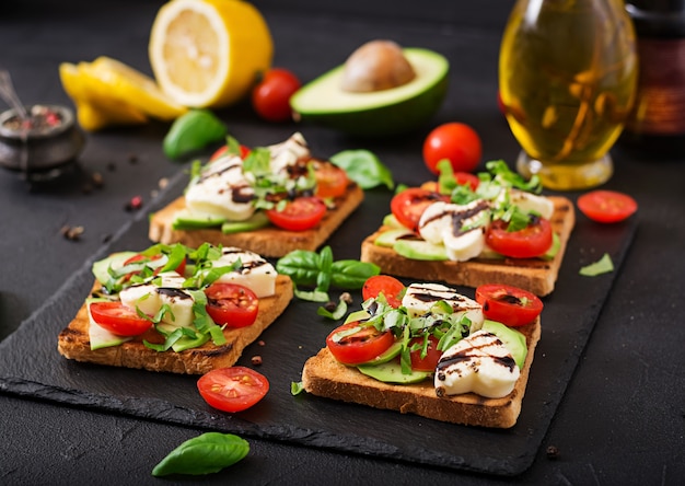 Pane tostato con pomodoro, mozzarella, avocado e basilico con aceto balsamico.