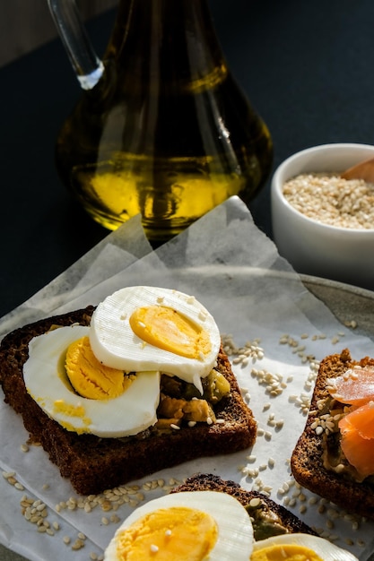 Pane tostato con uova in camicia, avocado e salmone. Panini al guacamole. Colazione salutare. Olio d'oliva. Semi di sesamo. Alimentazione sana vegetariana.