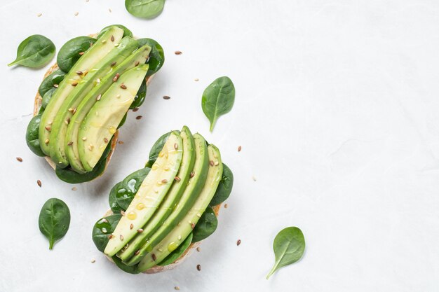 Pane tostato di due ciabatta con avocado affettato.