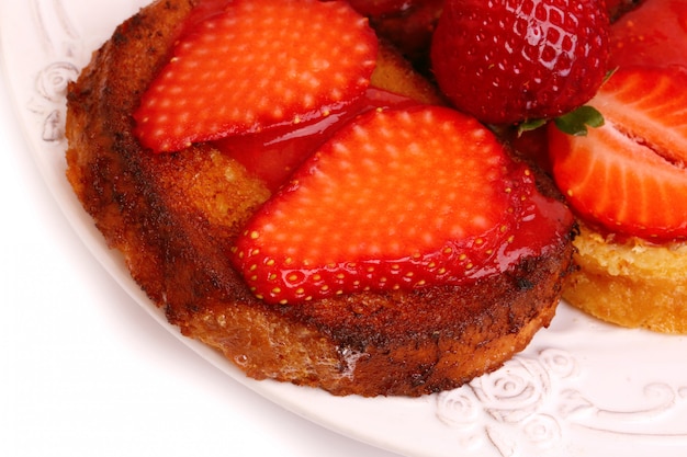 Pane tostato francese della prima colazione con le fragole isolate su fondo bianco