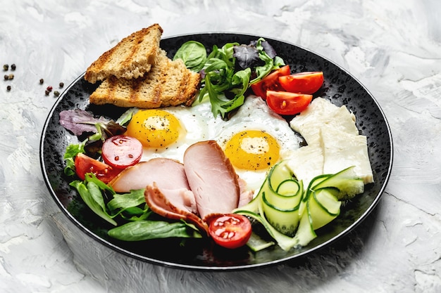 Pane tostato, uova, bacon e verdure inglesi della prima colazione. Deliziosa colazione o spuntino su uno sfondo chiaro, vista dall'alto.