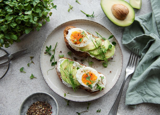 Pane tostato uova sode fetta di avocado microgreens su un piatto