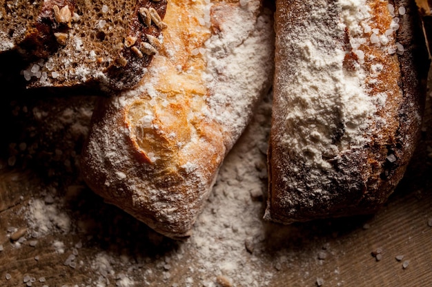 Pane tradizionale appena sfornato con farina sulla tavola di legno baguette fresca con farina