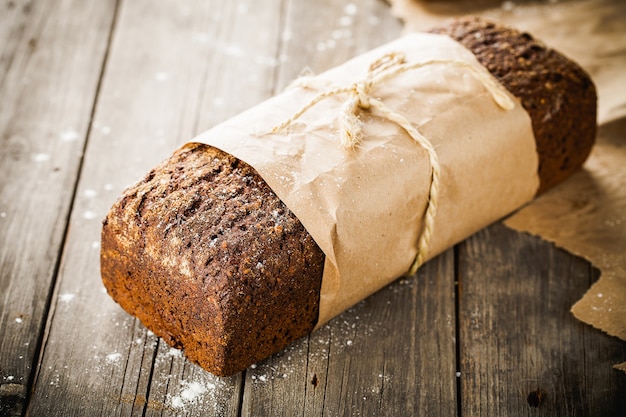 Pane tradizionale con semi avvolti in carta sul vecchio tavolo in legno