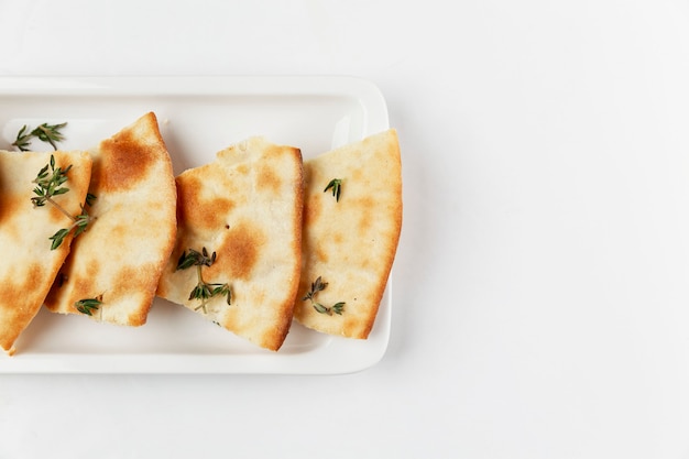 Pane tradizionale italiano con rosmarino. Fette appetitose su un piatto bianco. Sfondo bianco. Spazio per il testo. Avvicinamento.