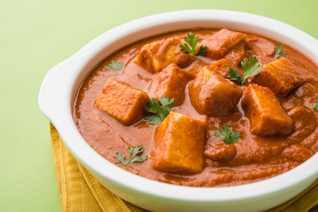 Paneer Butter Masala o Cheese Cottage Curry, popolare menu indiano per pranzo e cena servito a Karahi con Naan o Roti su sfondo lunatico, messa a fuoco selettiva