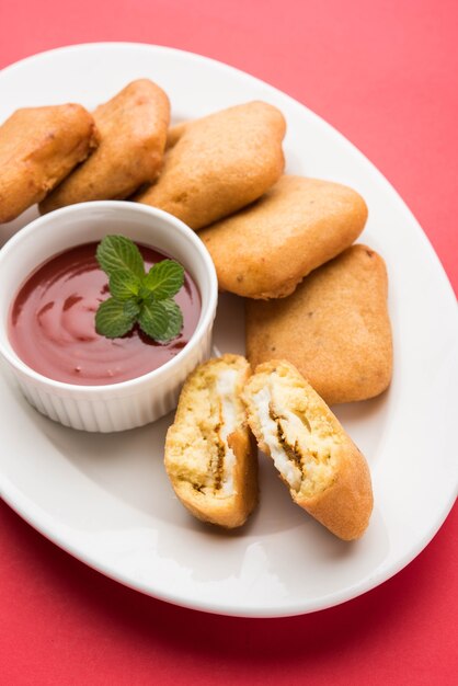 Paneer pakoras o Bhajji sono cubetti di ricotta piccanti ricoperti di farina di ceci o pastella di besan. Servito con ketchup di pomodoro in un piatto su sfondo colorato o in legno. Messa a fuoco selettiva