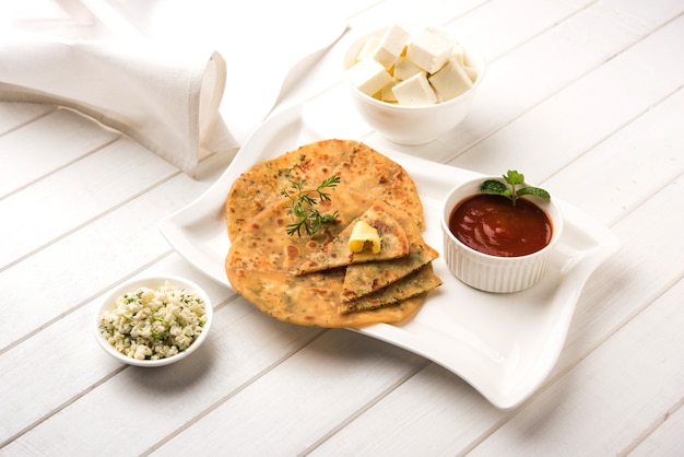 Paneer Paratha farcito con burro fuso, servito con cubetti di ricotta fresca e ketchup di pomodoro. Messa a fuoco selettiva