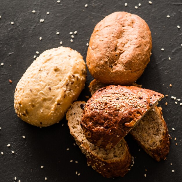 Panetteria artigianale. Pezzi assortiti con semi di sesamo su fondo nero