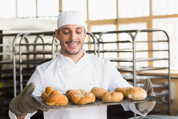 Panettiere che mostra vassoio di rotoli