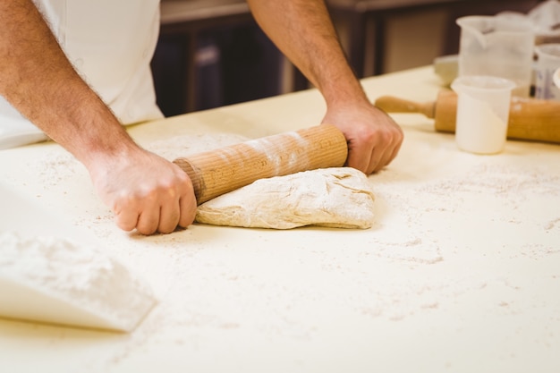 Panettiere che rotola la pasta a un bancone